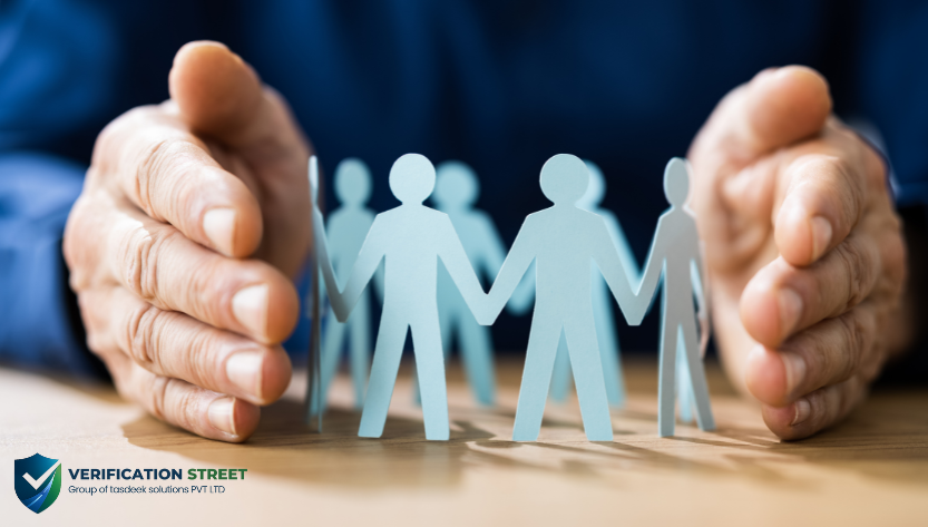 Employee Background Verification Hands protecting paper cutout people, showing employee background verification and workplace safety.